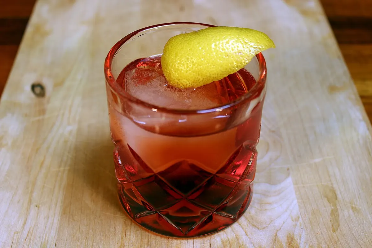 A Negroni cocktail served over ice in a rocks glass with an orange peel garnish