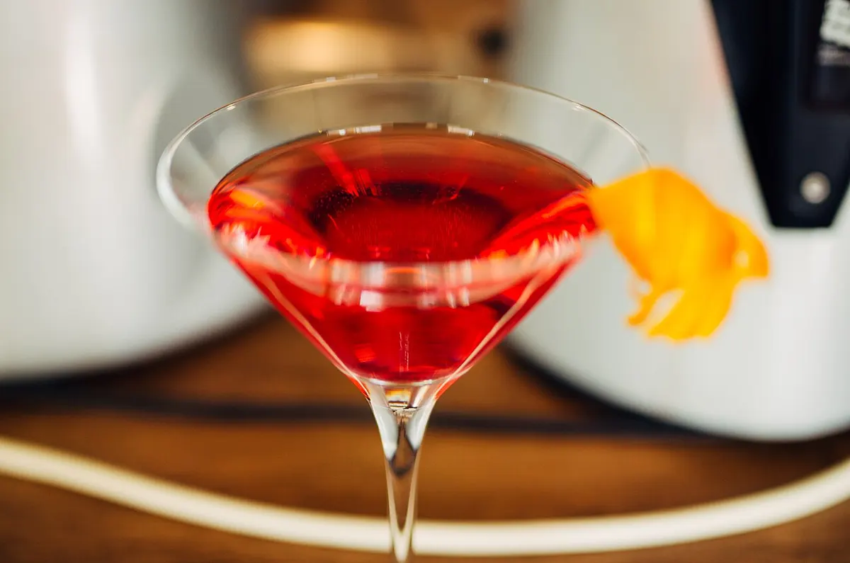 A whiskey cocktail garnished with an expressed citrus twist on a wooden bar